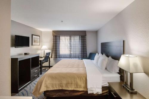 a hotel room with a large bed and a desk at Quality Inn Midvale - Salt Lake City South in Midvale