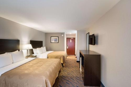a hotel room with two beds and a flat screen tv at Quality Inn Midvale - Salt Lake City South in Midvale