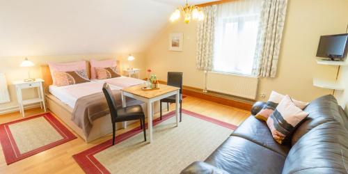 a bedroom with a bed and a table and a couch at Pension Gästehaus Heller in Weissenkirchen in der Wachau