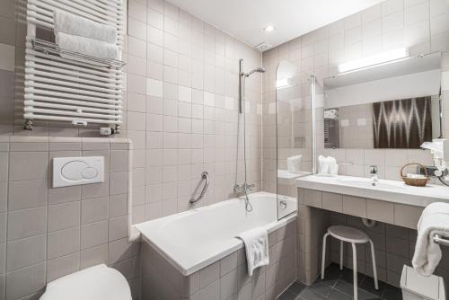 a white bathroom with a tub and a sink at Hotel Bourgoensch Hof in Bruges