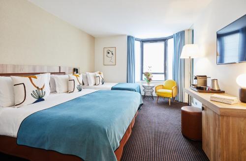 パリにあるプラザ トゥール エッフェルのベッド2台とテレビが備わるホテルルームです。