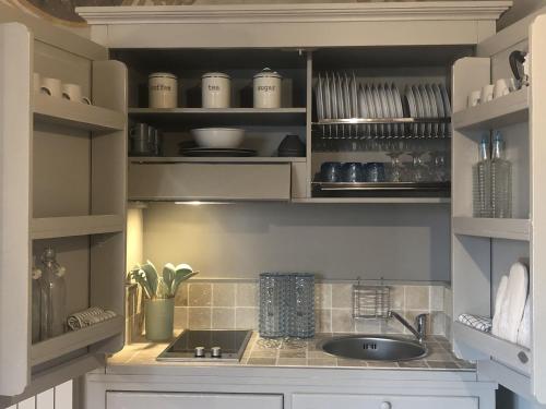 a kitchen with a sink and shelves with dishes at Little Liberty Loft in Barberino di Mugello