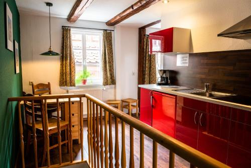 een keuken met rode kasten en een eetkamer bij Fachwerkhotel - Ferienhäuser Vorhof zur Hölle in Quedlinburg
