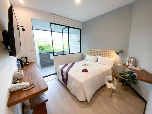 a bedroom with a bed and a desk and a television at Kenting Sunhow Inn in Kenting