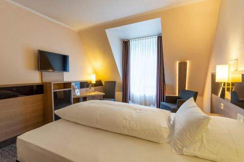 a hotel room with a bed and a television at Parkhotel Berghölzchen in Hildesheim