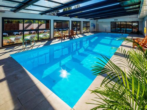 a large swimming pool with blue water at Garrigae Manoir de Beauvoir Poitiers Sud - Hotel & Spa in Mignaloux-Beauvoir