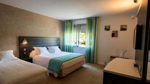 a hotel room with two beds and a window at Logis Hotel Restaurant SPA Les Oliviers in Loriol-sur-Drôme
