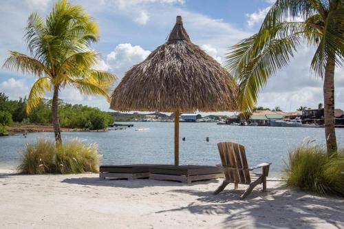 a beach with a straw umbrella and a chair and water at Spanish Water A1 in Willemstad