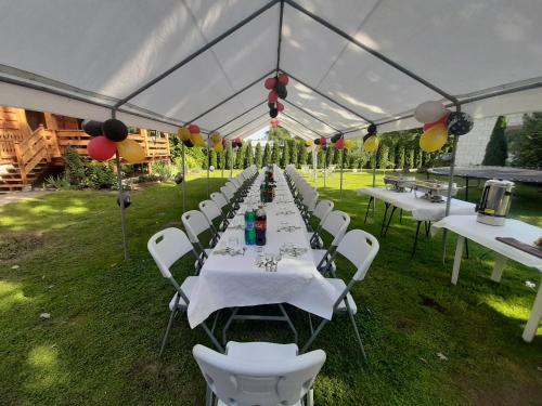 a row of white tables and chairs under a marquee at Dom Wilków in Leoncin
