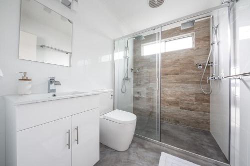 a bathroom with a toilet and a glass shower at Salty Kisses Holiday House in Point Clare