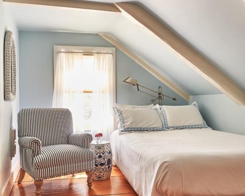 ein Schlafzimmer mit einem Bett, einem Stuhl und einem Fenster in der Unterkunft Cliff Lodge in Nantucket