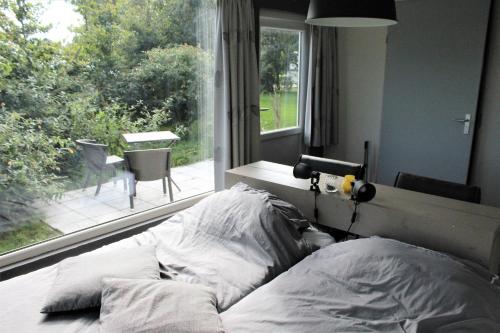 a bed in a bedroom with a large window at Panorama Box op Camping de Stal in Drijber