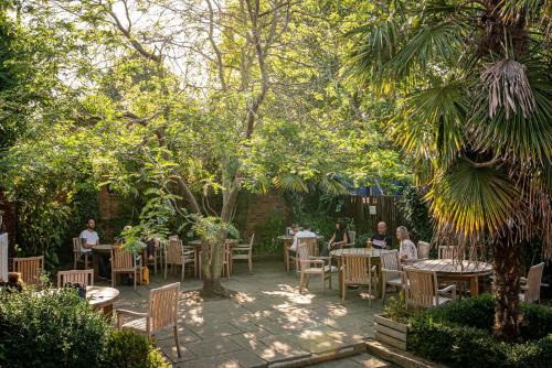 a group of people sitting at tables in a garden at The Sun Inn in Faversham