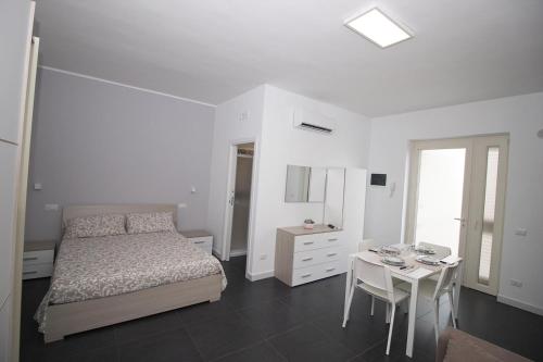 a white bedroom with a bed and a table at Puglia casa vacanza in Ginosa Marina