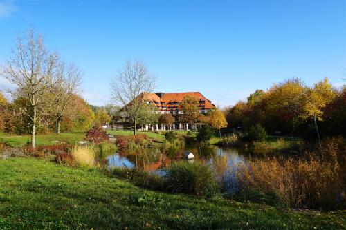 a house with a pond in front of it at Flair Park Hotel Ilshofen in Ilshofen