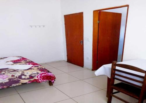 a bedroom with a bed and a door and a chair at Pousada Brasil - Self Check-in in Aparecida