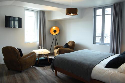 a bedroom with a bed and two chairs and a television at une nuit sur le pont 1 in Landerneau