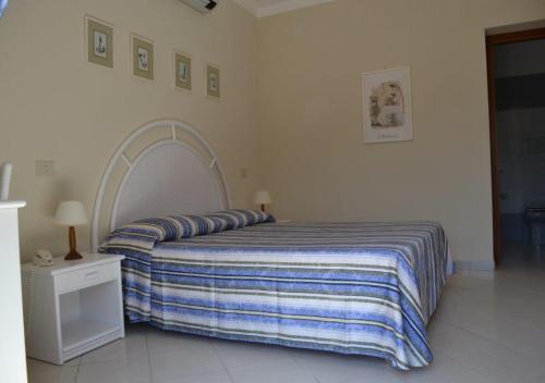 a bedroom with a bed with a striped blanket at Hotel Danila in Portoferraio