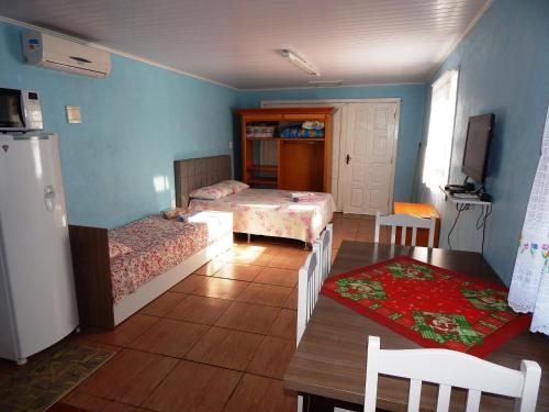 Habitación con 2 camas, mesa y nevera. en Residenciais Casa Verde Gramado, en Gramado