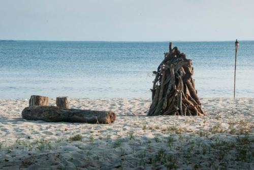 a wooden bench sitting on top of a sandy beach at Hotel Playa Manglares Isla Baru in Barú