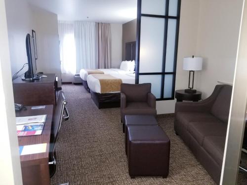 a hotel room with a bed and a couch and a television at Comfort Suites Little Rock West in Little Rock