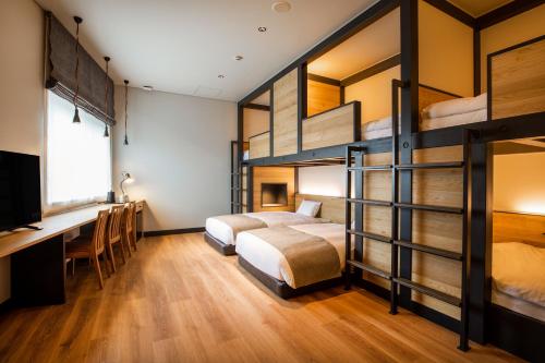 a bedroom with two bunk beds and a desk at HOTEL KARUIZAWA CROSS in Karuizawa