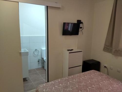 a bedroom with a bed and a bathroom with a television on the wall at Kiki vivienda Bed & breakfast in San Isidro