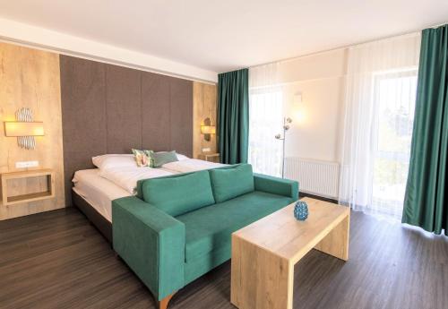 1 dormitorio con 1 cama y 1 sofá verde en Luxstay Karben Neue Mitte - Self-Check-In en Karben