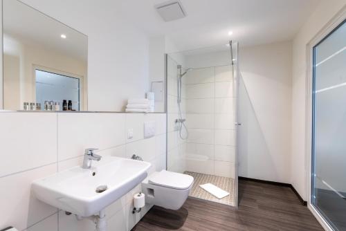 a white bathroom with a sink and a shower at Luxstay Karben Neue Mitte - Self-Check-In in Karben