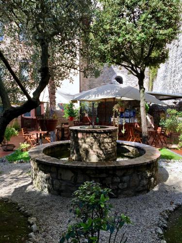 a stone fountain in a park with trees and tables at Relais Ducale in Gubbio