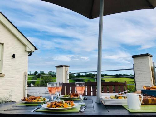 a table with plates of food and glasses of wine at Red Kite Cottage in Carmarthen