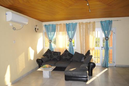 a living room with a black couch and blue curtains at Résidence Hotelière Borel Denver in Douala