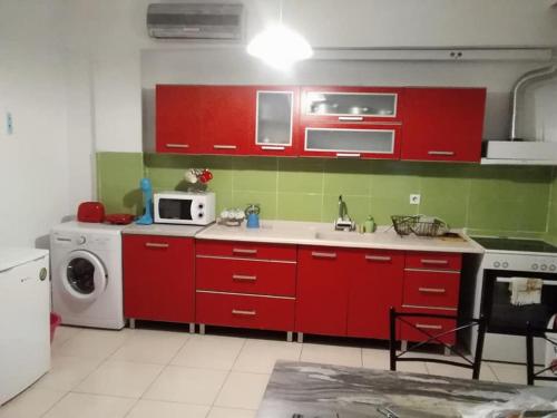 uma cozinha com armários vermelhos e uma máquina de lavar roupa em kipselis dep em Xanthi