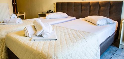 two beds in a hotel room with towels on them at Hotel Alos in Almirós