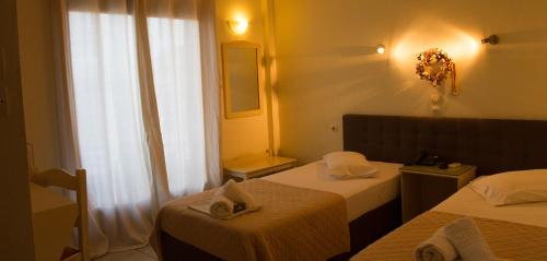 a hotel room with two beds and a window at Hotel Alos in Almirós