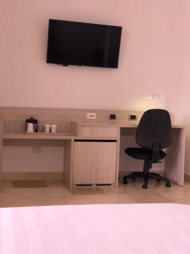 a desk with a chair and a television on a wall at Radisson Diamond Barranquilla in Barranquilla