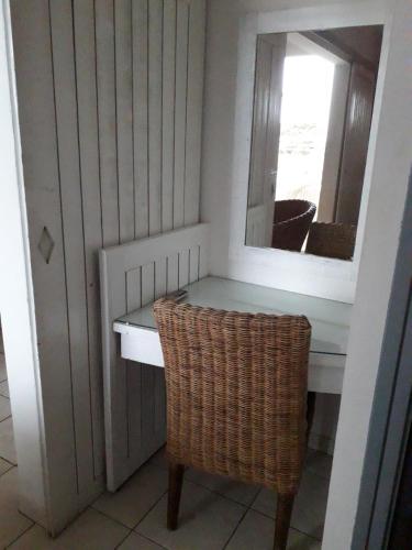 a dressing table with a mirror and a chair at Appartement Colibri de la Baie de Tartane in La Trinité