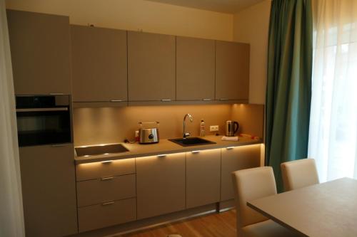 a kitchen with white cabinets and a sink and a table at Meyn's Apartments & Hotel in Soltau