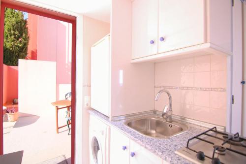 una cocina con armarios blancos y fregadero en Apartamento Muralla Roja 0507, en Calpe