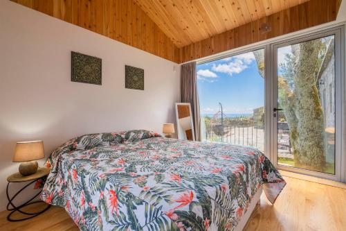 a bedroom with a bed and a large window at Casa do Castanheiro - Nordeste, Açores in Nordeste