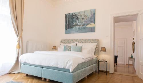 a bedroom with a large bed with white sheets and blue accents at Palais Gutenberg la Ville in Klagenfurt