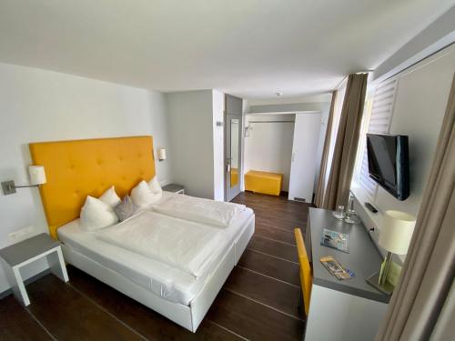 Dormitorio con cama, escritorio y TV en Altstadthotel Baunachshof, en Wertheim