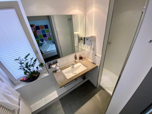 La salle de bains est pourvue d'un lavabo et d'un miroir. dans l'établissement Altstadthotel Baunachshof, à Wertheim
