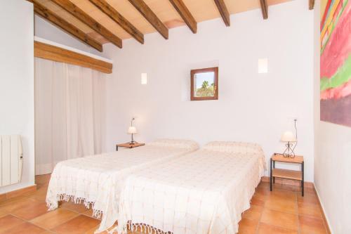 een witte slaapkamer met een bed en 2 tafels bij Finca Bonita in Son Servera