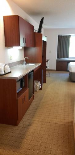 a kitchen with wooden cabinets and a sink in a room at Microtel Inn & Suites by Wyndham Wellsville in Wellsville