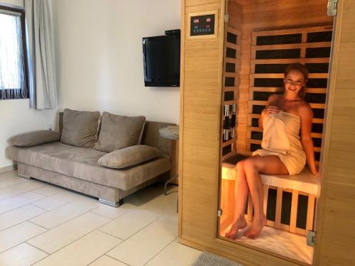 a woman sitting on a bench in a wine cellar at Mandula Apartman in Cegléd