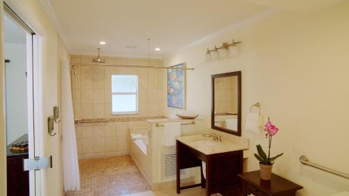 a bathroom with a sink and a tub and a mirror at Coconut Palm Inn in Key Largo