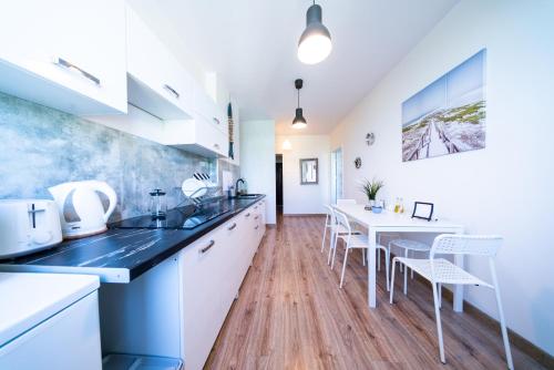 a kitchen with white cabinets and a table and chairs at Apartament Blue Sea Gdynia in Gdynia