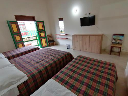 a bedroom with two beds and a flat screen tv at Balcones del Parque Jardin in Jardin