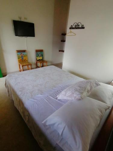 a bedroom with a white bed with a flat screen tv at Balcones del Parque Jardin in Jardin